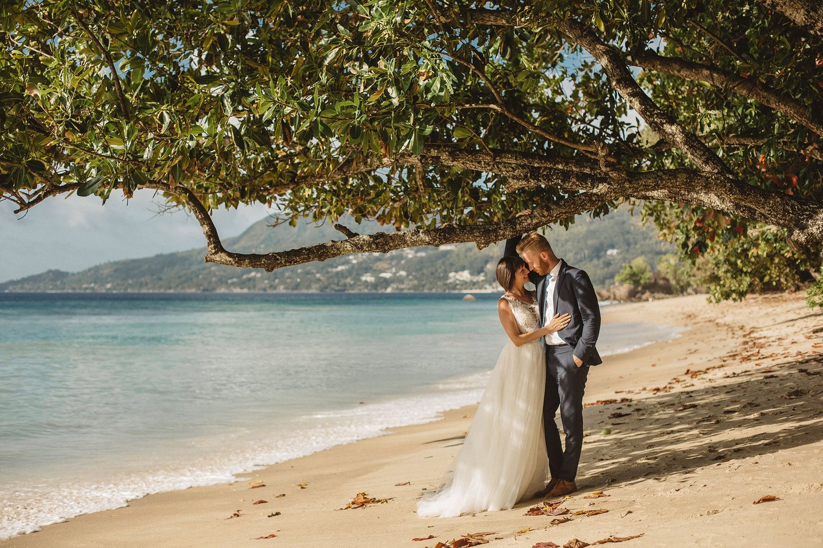 Bride and groom silhouetted against turquoise Seychelles ocean at golden hour