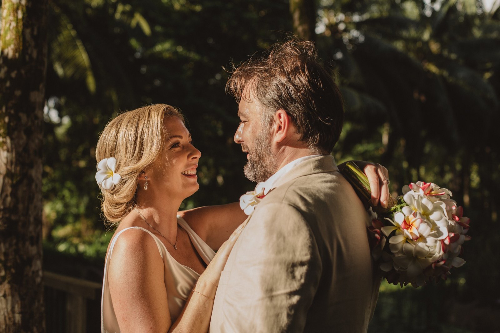 A bride and groom embrace in cinematic golden-hour light on a Seychelles beach — luxury destination wedding photography by To Happy Endings